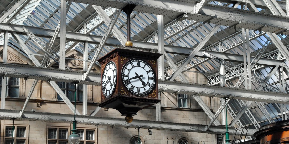 Steel roof beams and glass in old railway station building with large hanging clock