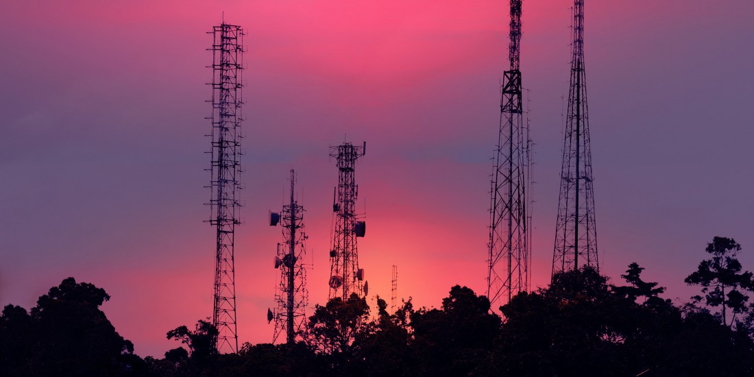 Silhouette of cell towers against a sunset sky